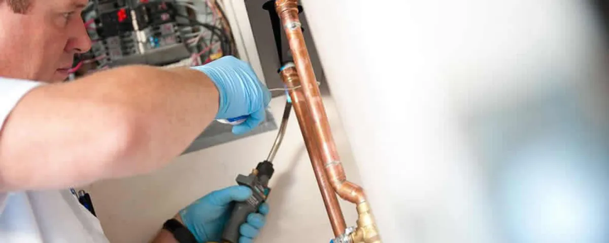 Water heater repair technician testing copper pipe connections and controls in Indianapolis, IN